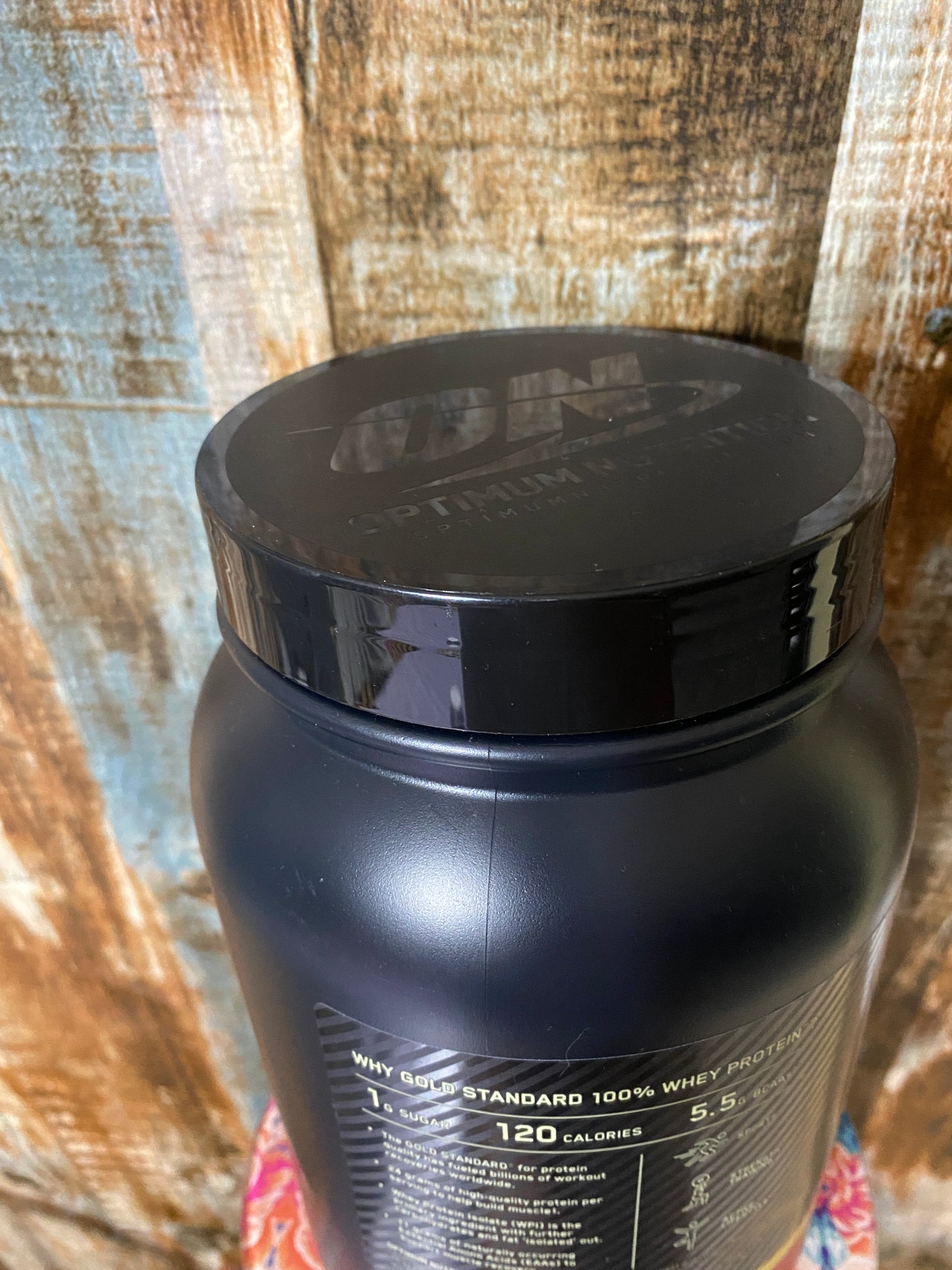 Black protein powder container on a wooden surface